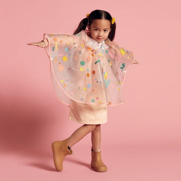 女の子がレインケープを着て両手を広げています。