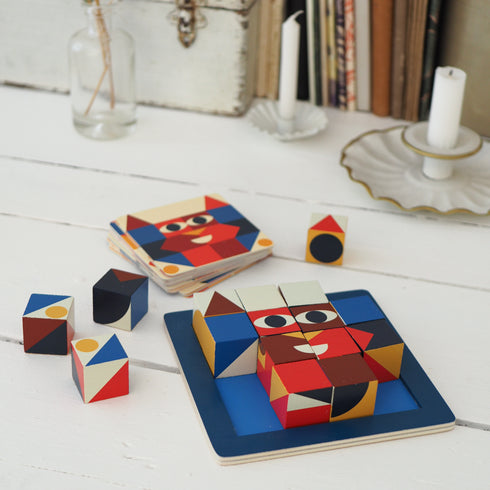 「キューブ ロジック 16」がテーブルの上に置かれています。キューブはまわりに散らばっていて、カードの絵柄のとおりに完成していません。